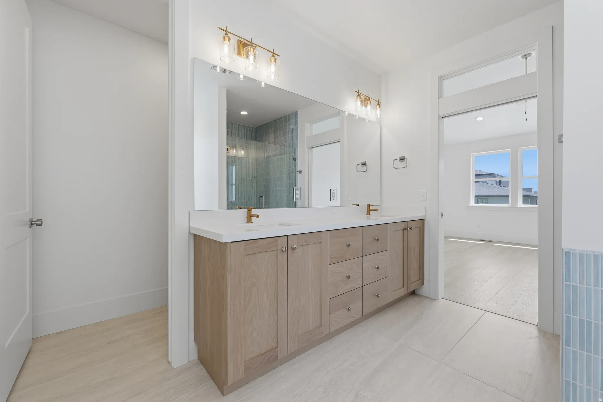 Primary Suite. Dual vanity with light wood-finish cabinetry and white countertop