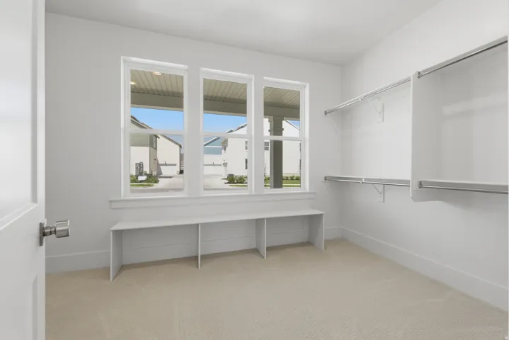 Primary Suite. Carpeted room with multiple windows, a built-in bench, and built-in closet shelving