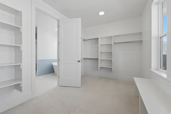 Primary Suite. Built-in shelving, integrated hanging rods, recessed lighting, window, and carpet flooring