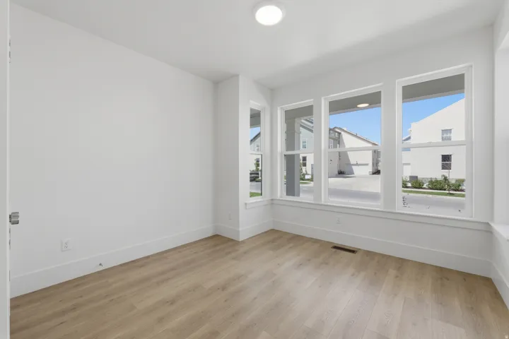 Light wood-finish flooring, white walls, and multiple large windows