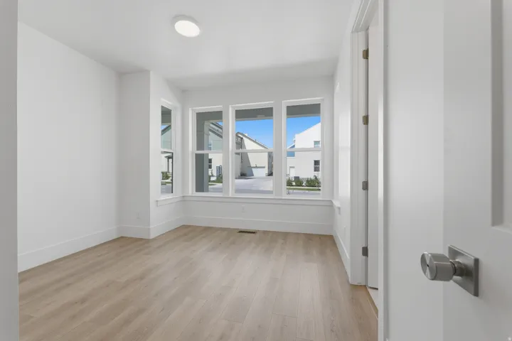 level one guest bedroom with ensuite bathroom. Neutral wall finishes, wood-finish flooring, recessed ceiling lighting, multi-pane windows, and a modern door handle