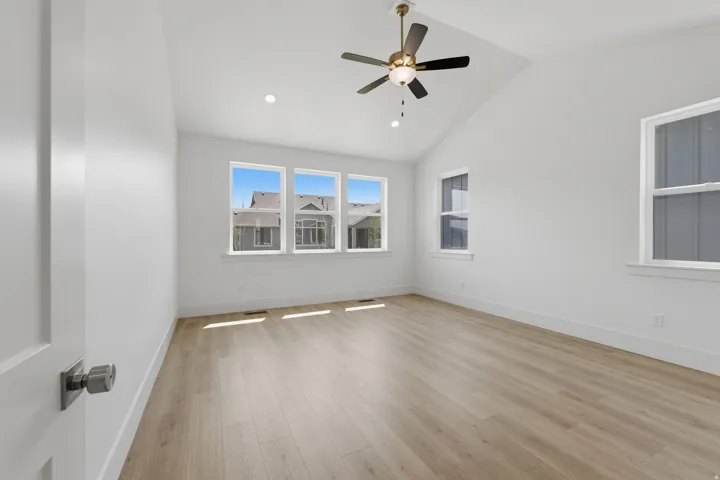 Primary Suite. Vaulted ceiling with a ceiling fan, recessed lighting, wood-finish flooring, and multiple windows