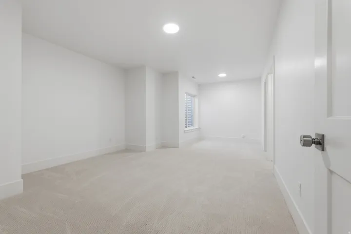 Basement bedroom with ensuite bathroom. Neutral tone carpet flooring with white walls, recessed ceiling lighting, and a single window