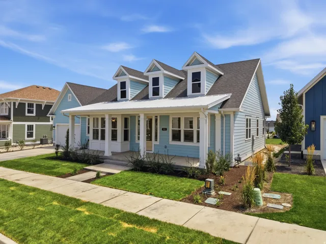 Light blue clapboard siding with white trim, dark shingle roof, and a covered front porch