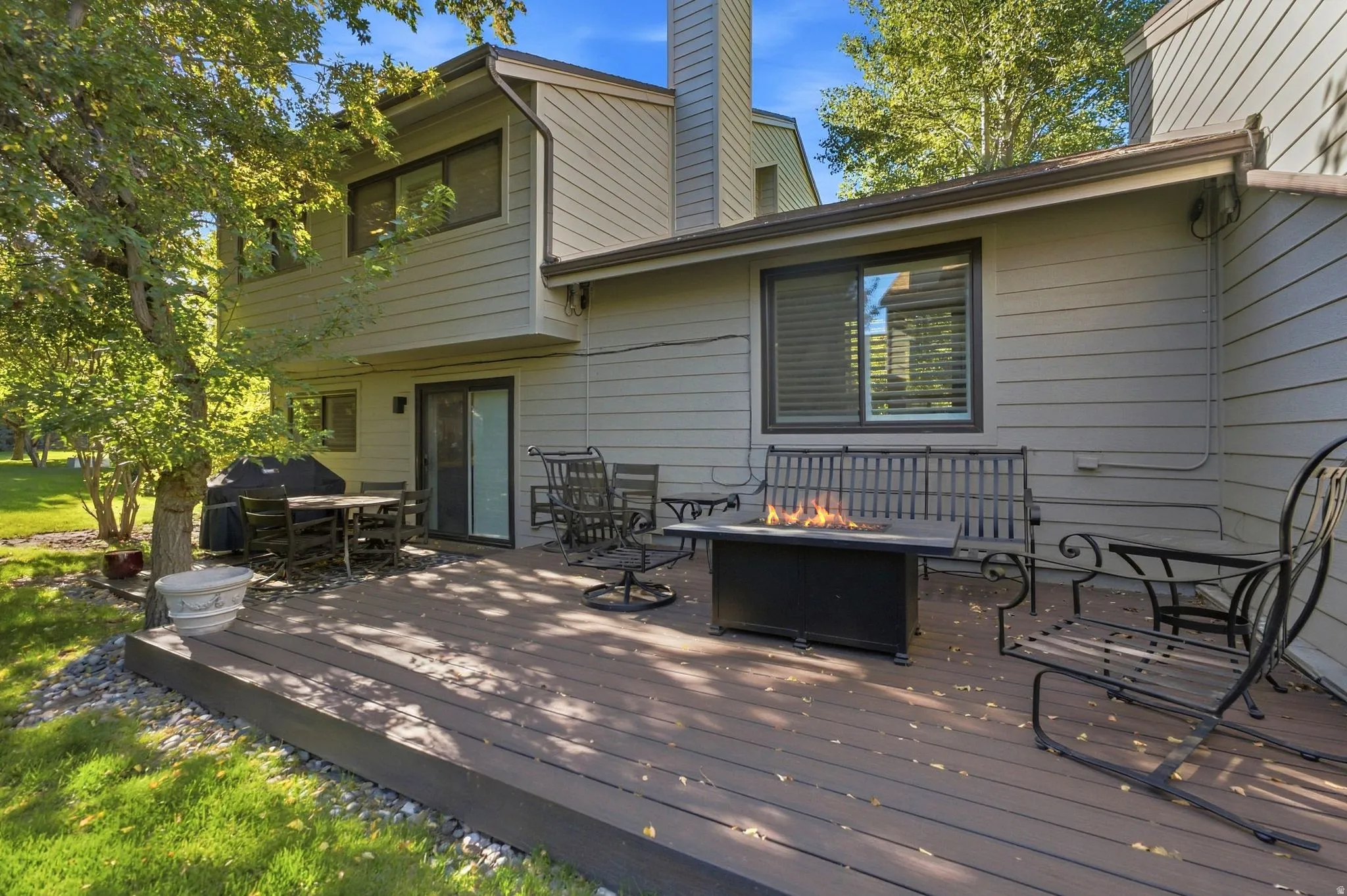 Spacious outdoor deck with composite decking, mature trees, and a sliding glass door for outdoor access