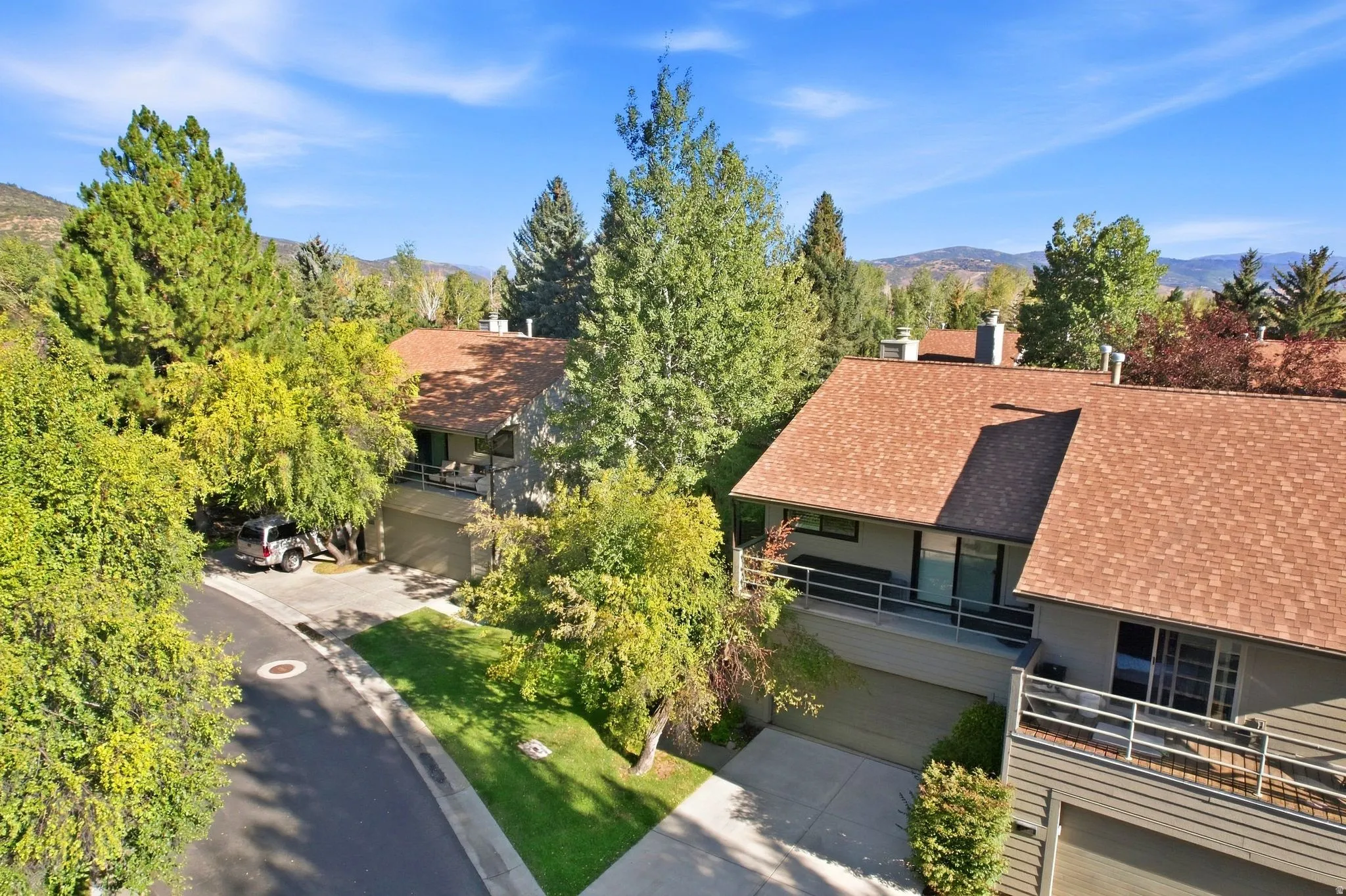 Multi-level exterior with shingle roofing, integrated garages, and private balconies featuring metal railings