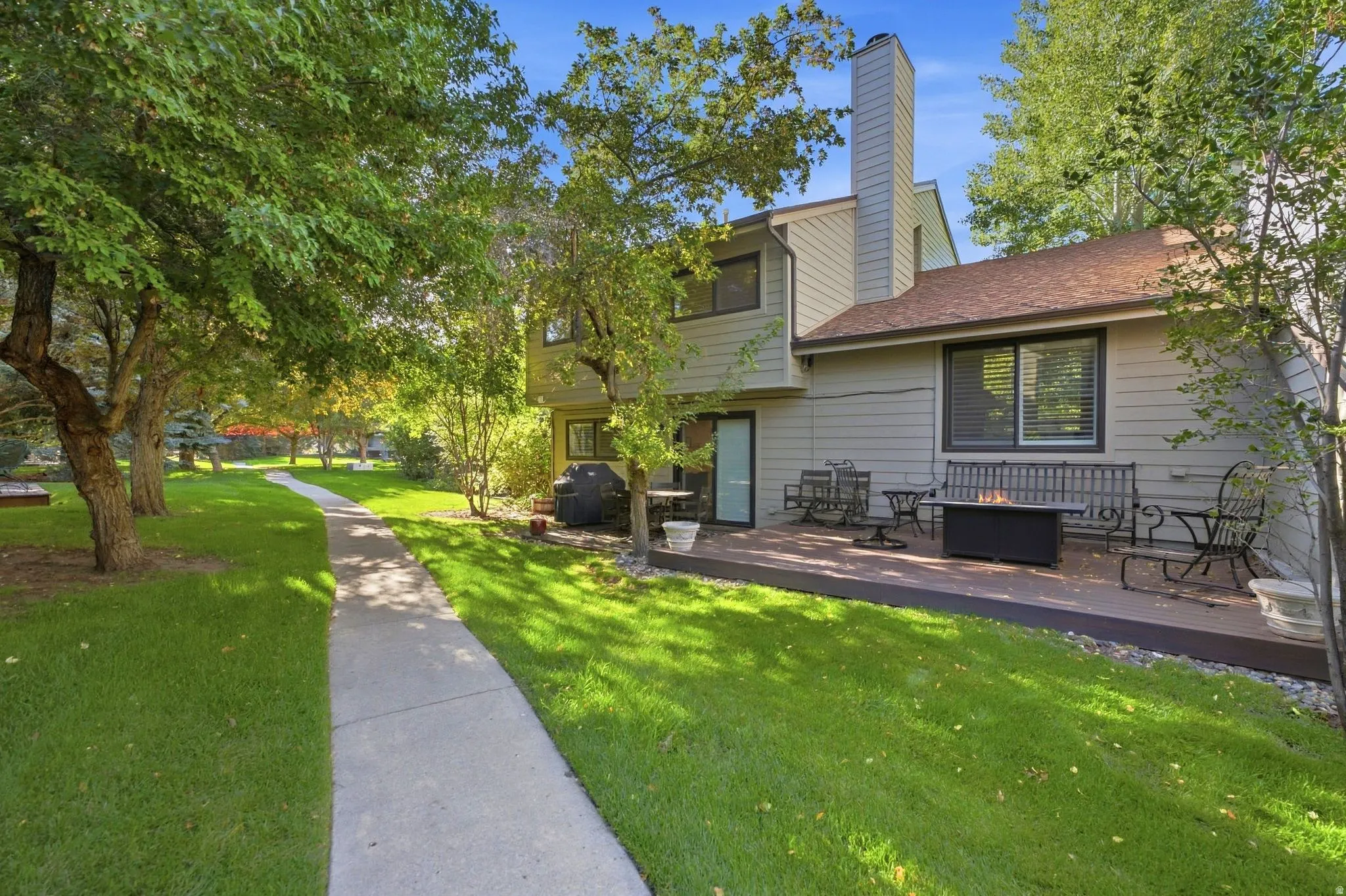 Expansive lawn with mature trees and a paved walkway