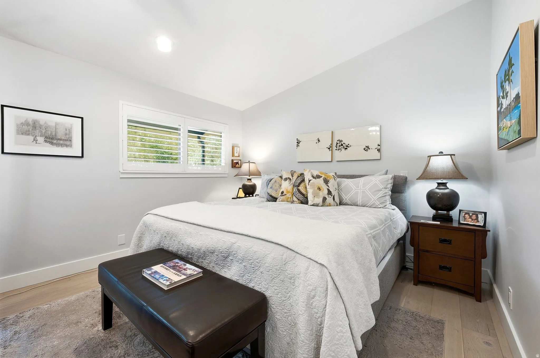 Light-toned wood-finish flooring, white walls, and a window with white plantation shutters