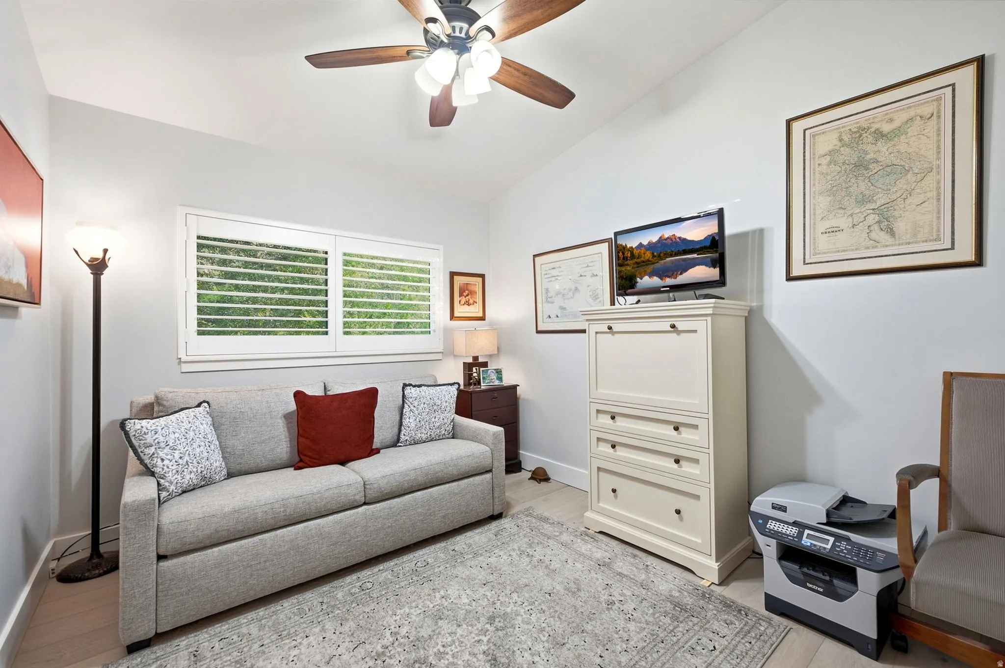 Vaulted ceiling with a ceiling fan, light-toned wall paint, plantation shutters, and wood-finish flooring