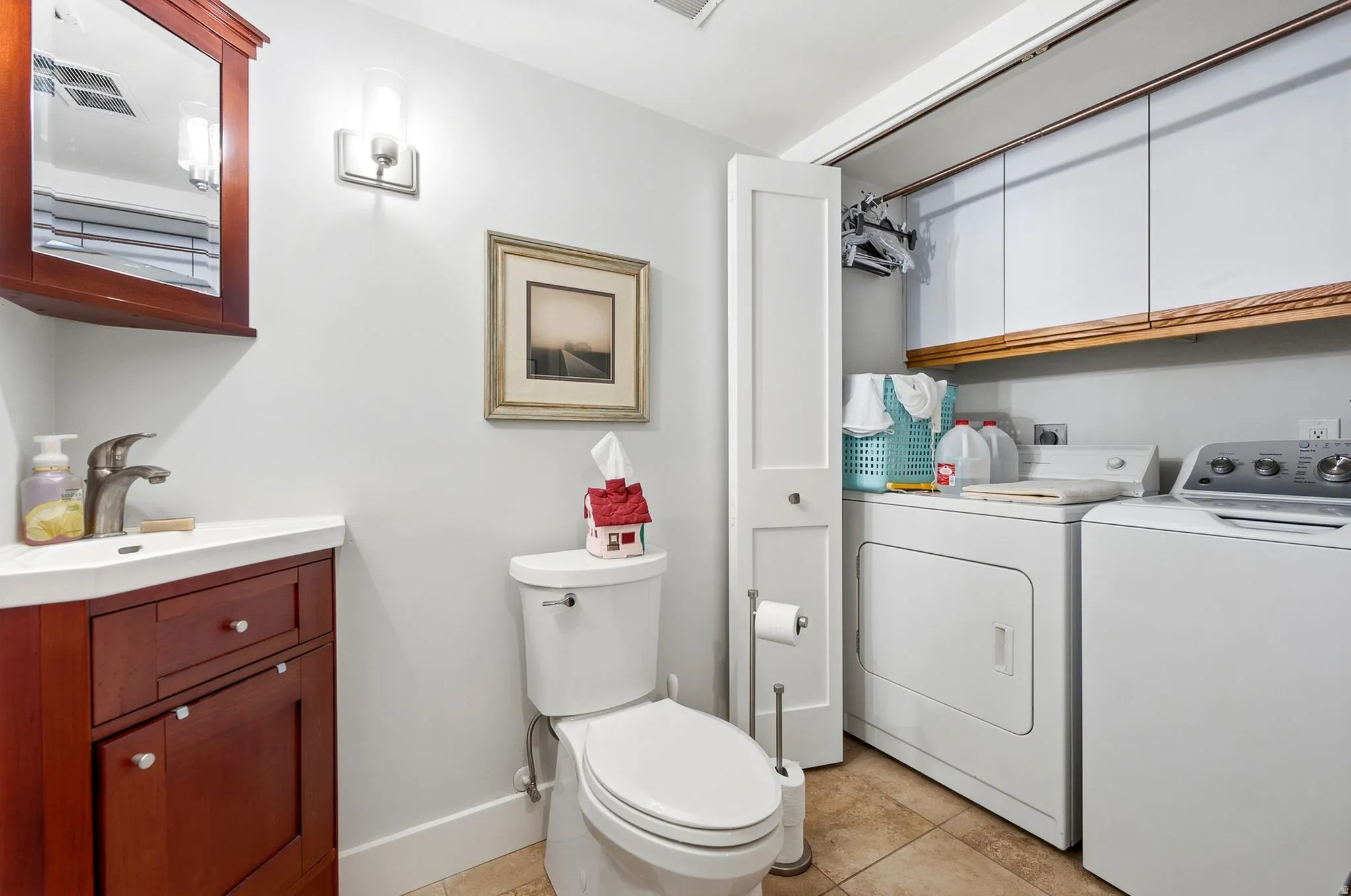 Integrated laundry area with upper cabinetry, a built-in hanging rod, and tile flooring
