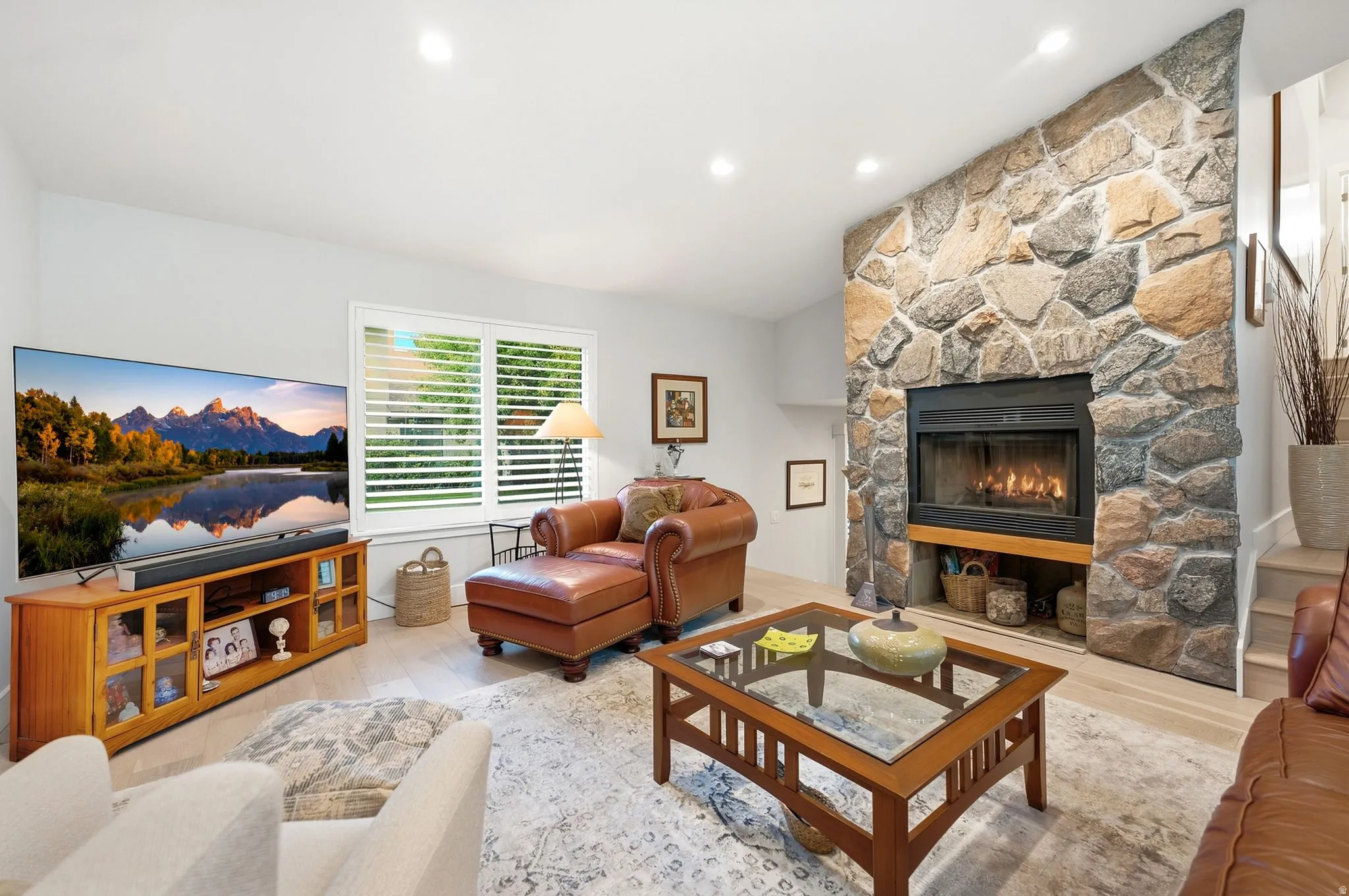 Stone-faced fireplace with a built-in firebox, recessed lighting, and light wood-finish flooring throughout
