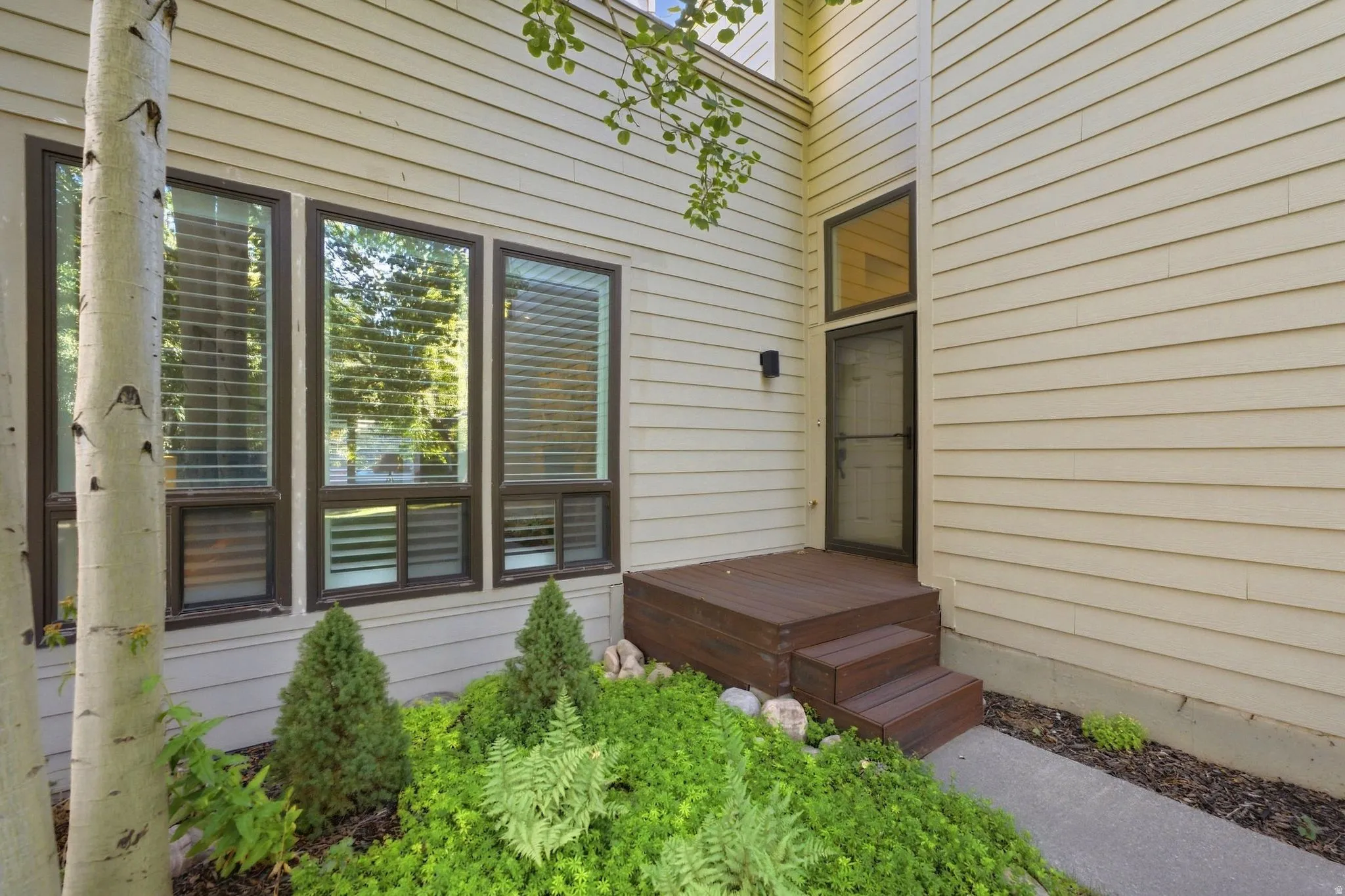 Fiber cement siding exterior with a composite deck and steps, large windows, and manicured landscaping