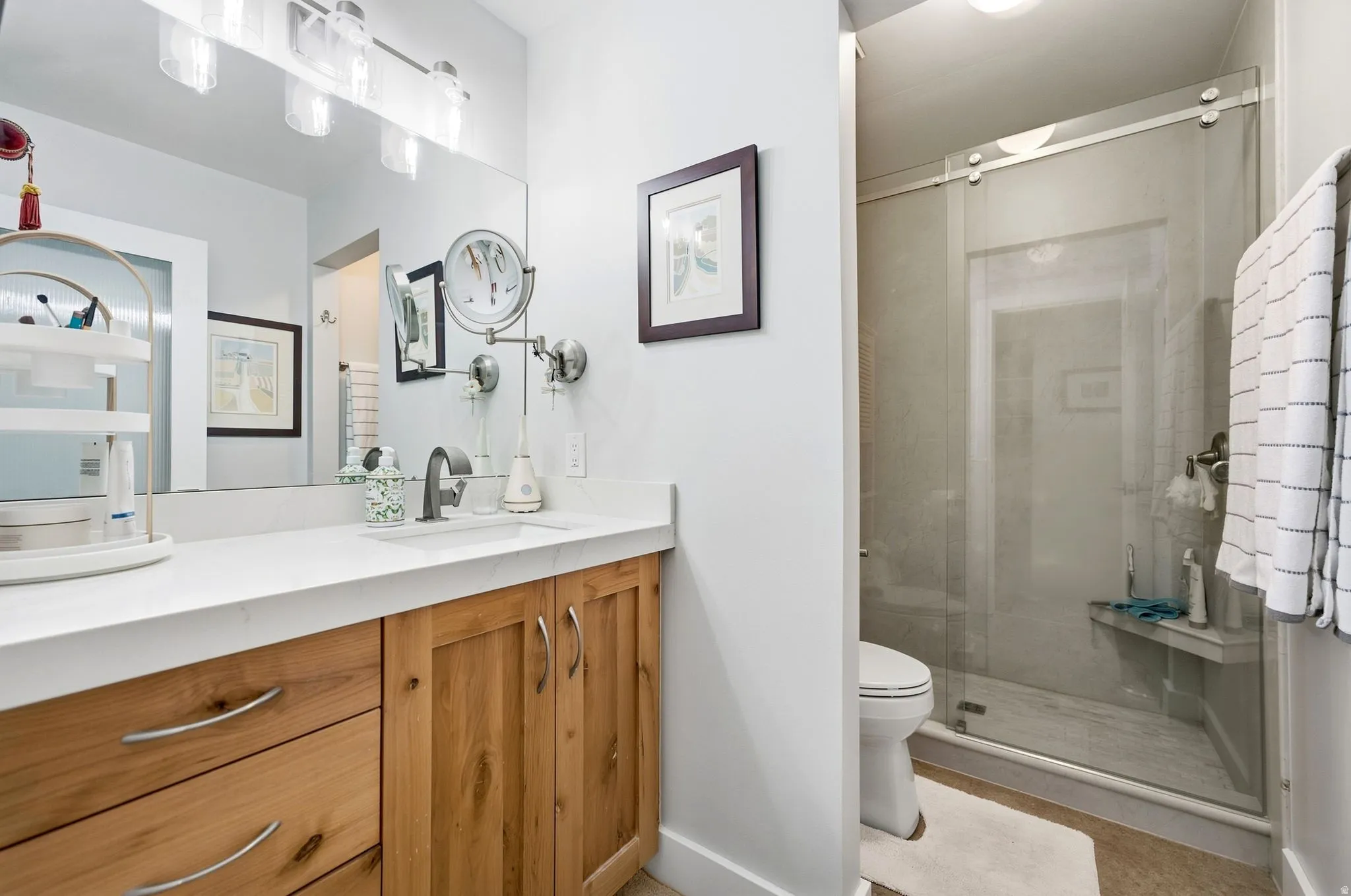 Wood-finish vanity with white countertop, undermount sink, and wall-mounted mirror - large walk-in shower.