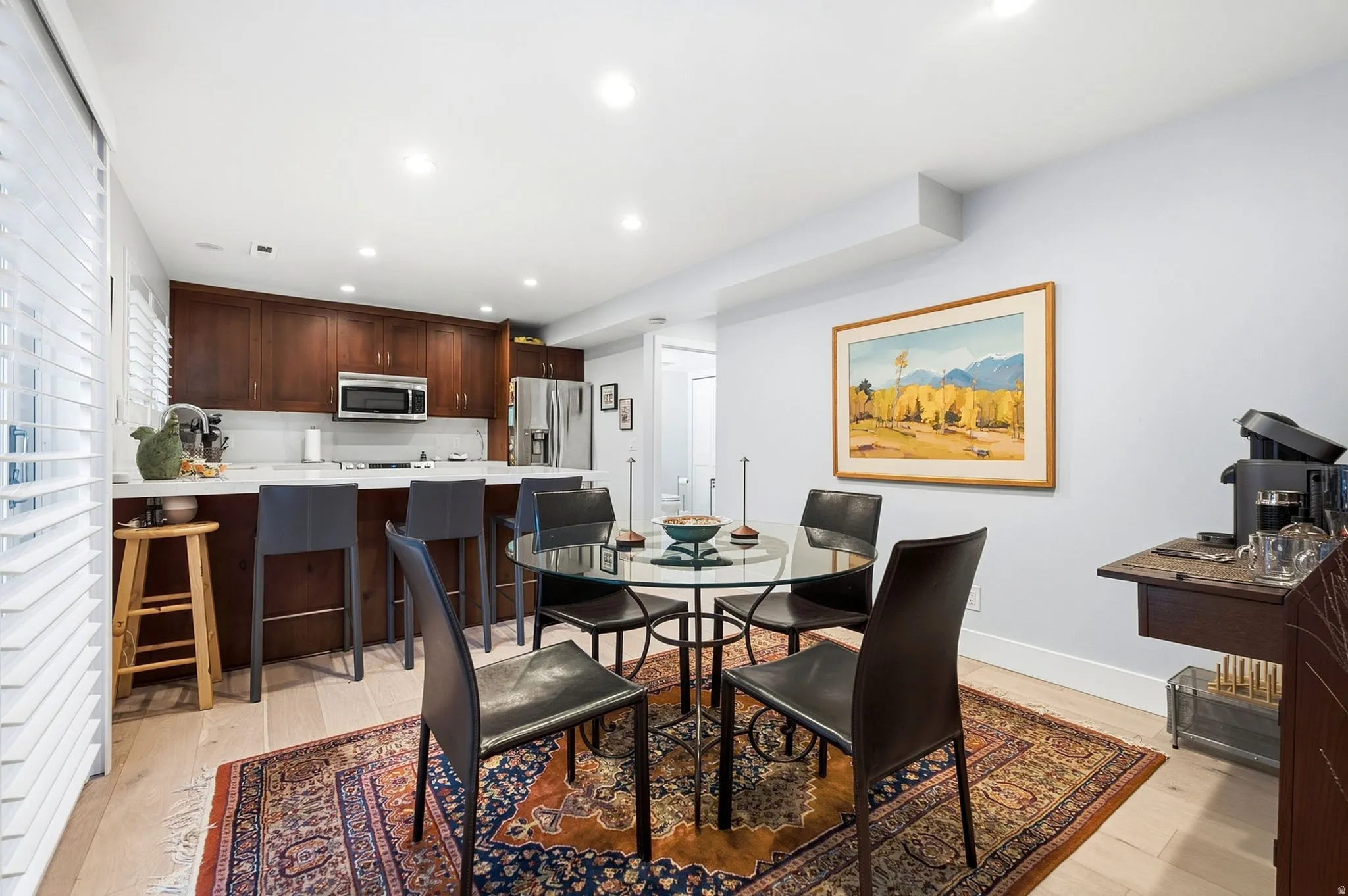 Kitchen featuring dark wood cabinetry, stainless steel appliances, a white tile backsplash, and a breakfast bar with seating