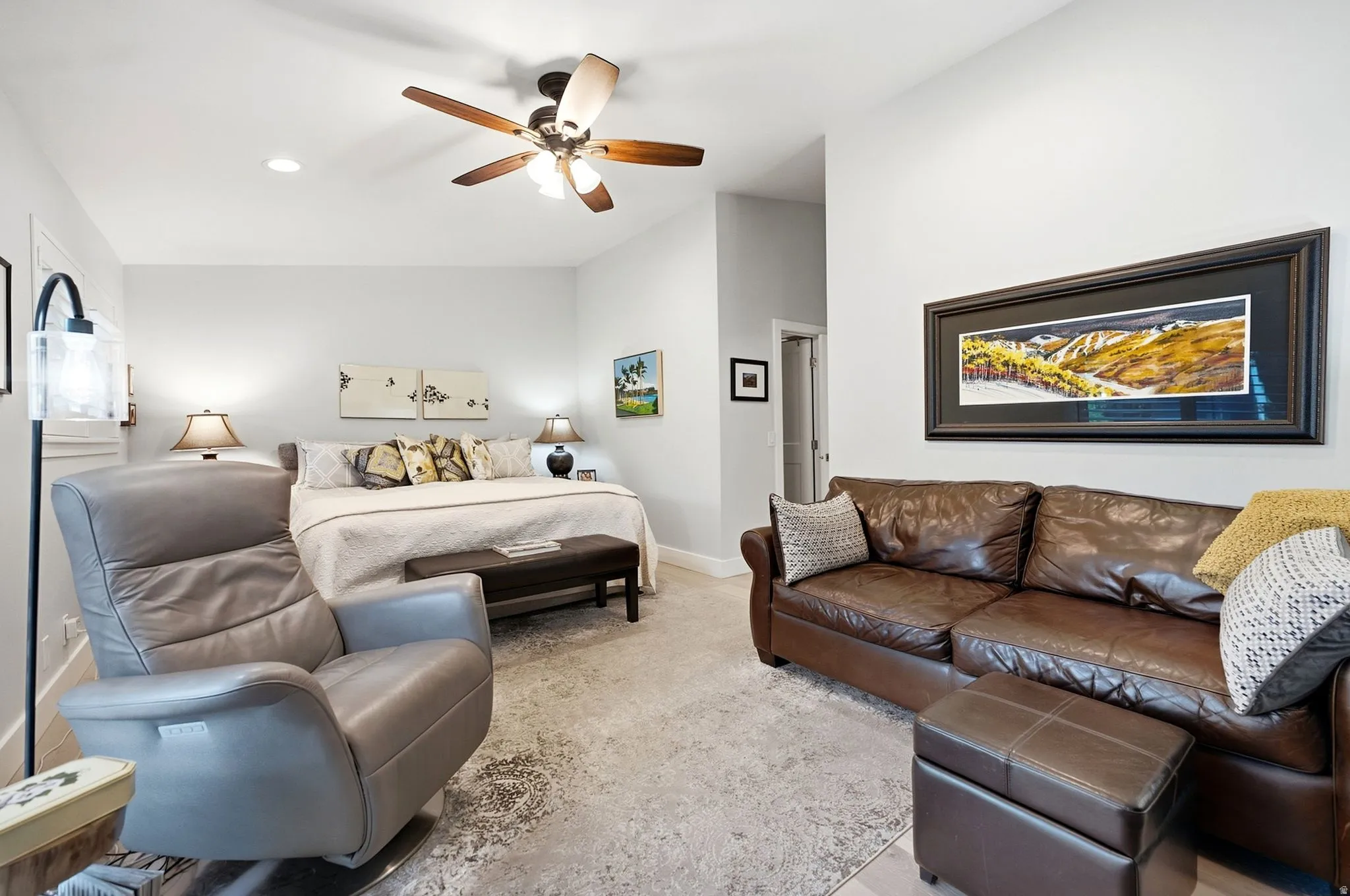 Recessed lighting, ceiling fan with wood-finish blades, and neutral-toned walls
