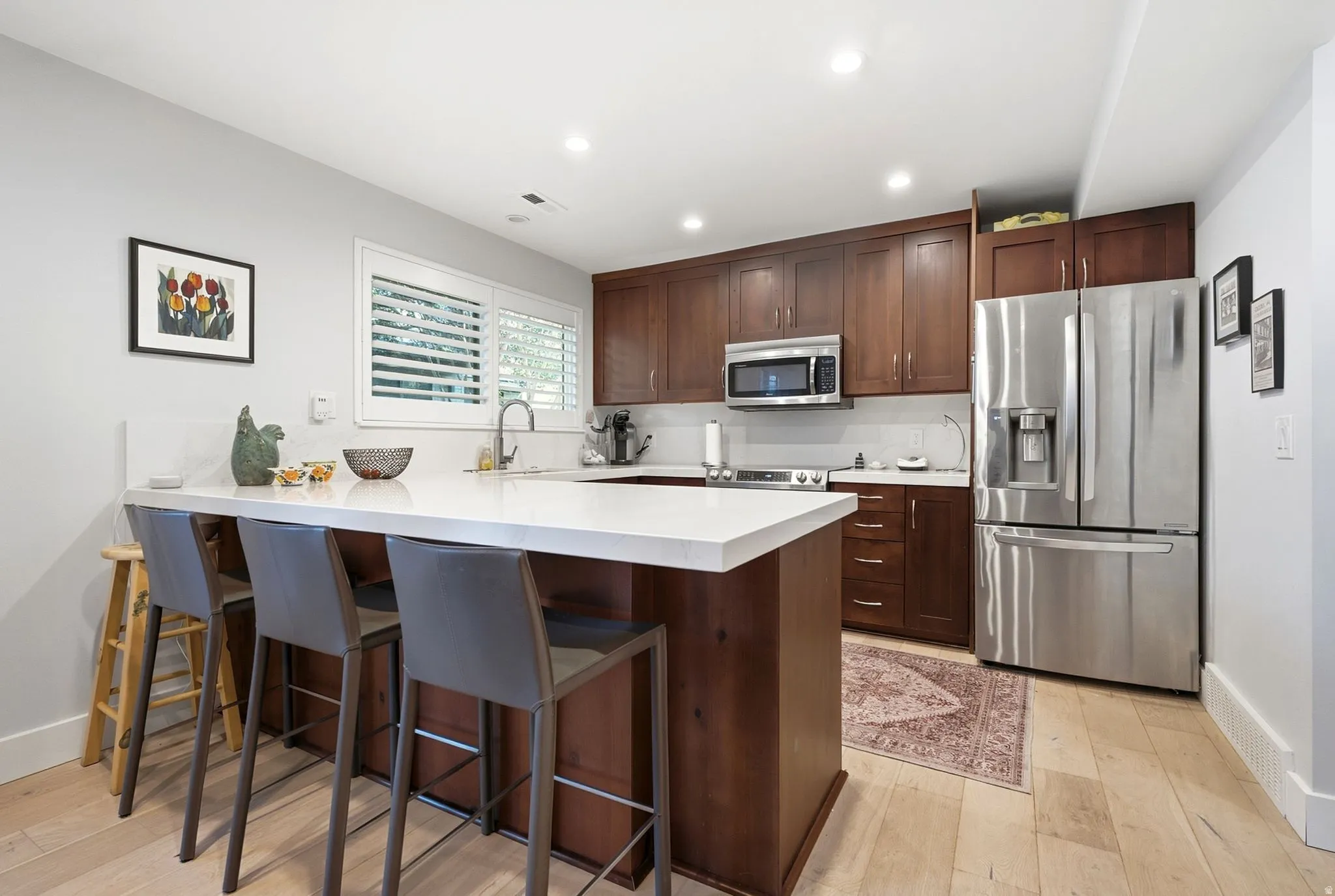 Kitchen featuring a center island with countertop seating, wood-finish cabinetry, stainless steel appliances, and light wood-finish flooring