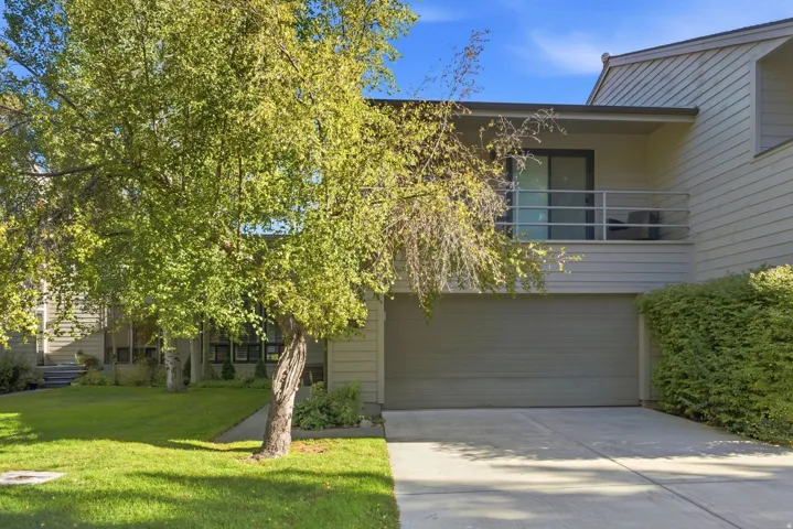 Exterior featuring horizontal siding, an attached garage, a second-story balcony with metal railings, a concrete driveway, and a manicured lawn