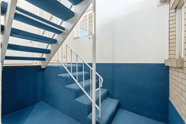 Carpeted staircase with white metal railings and a white painted door