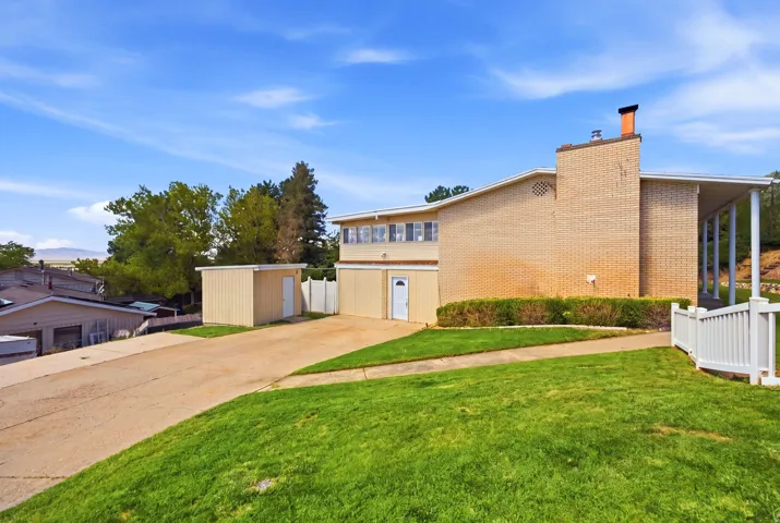 Brick exterior with a covered entryway, attached storage shed, and a concrete driveway
