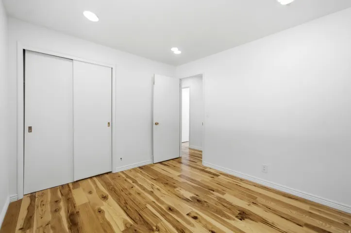 Recessed lighting, wood-finish flooring, white walls, and built-in sliding closet doors