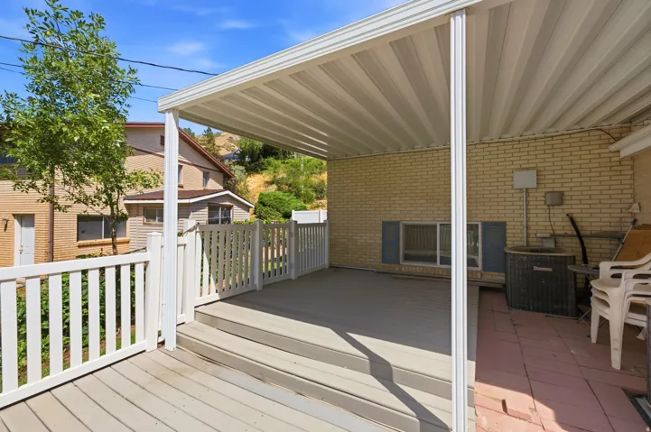 Covered deck with composite decking, white picket railing, and brick exterior wall