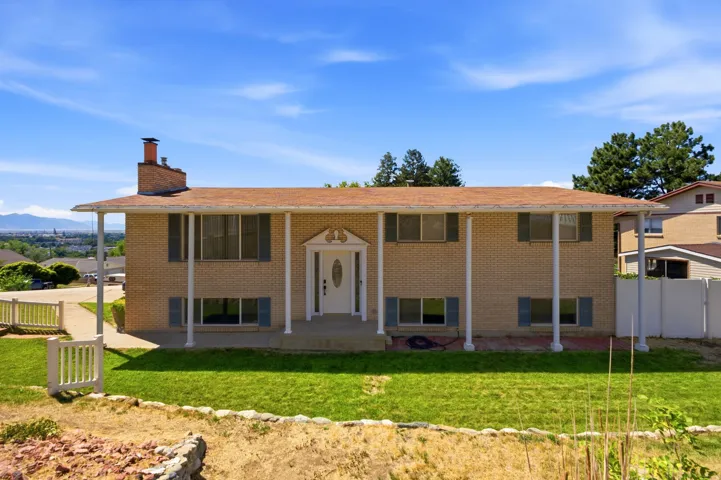 Brick exterior with a covered porch, white columns, and a front lawn