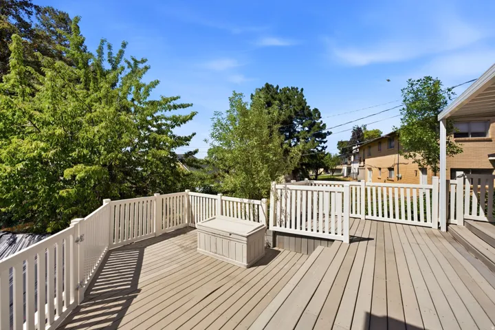 Expansive outdoor deck featuring wood-finish flooring and white railings