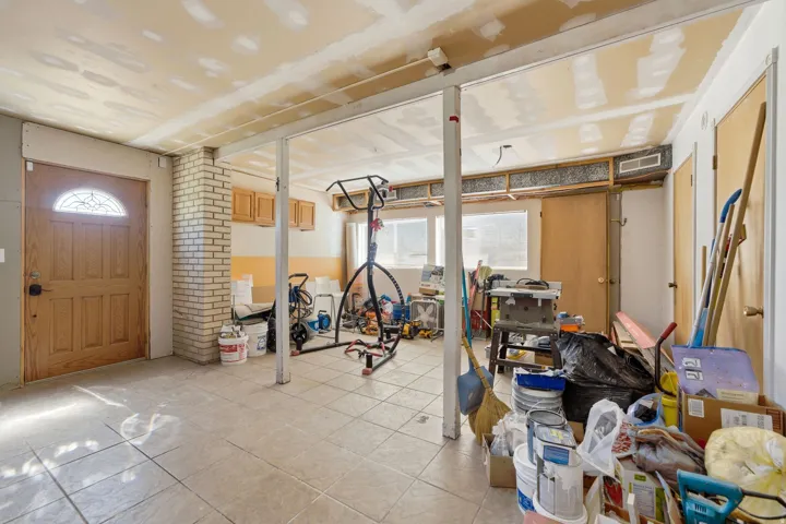 Tiled flooring throughout, exposed ceiling joists, and a decorative wood-paneled door with an arched glass insert