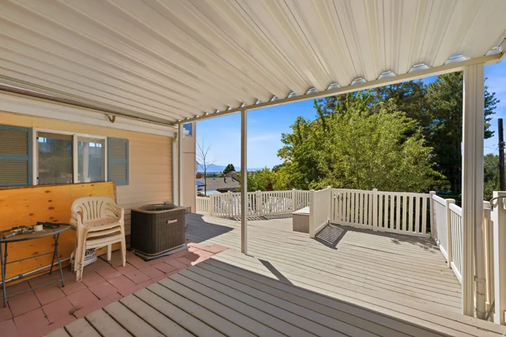Expansive covered deck featuring a metal awning and white railing