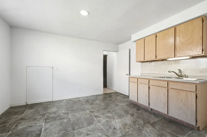 Kitchenette with light wood cabinetry, a stainless steel sink, and a laminate countertop