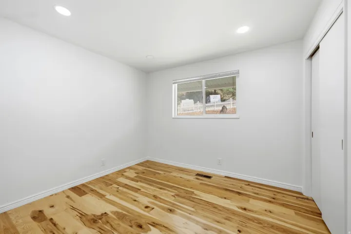 Recessed ceiling lighting, wood-finish flooring, and white walls