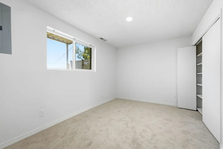Recessed ceiling lighting, white walls, carpet flooring, window, and built-in closet shelving