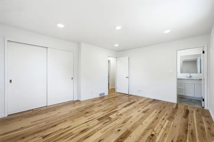 Wood-finish flooring, recessed lighting, and white sliding closet doors