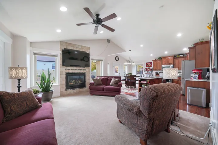 Vaulted ceiling with recessed lighting, ceiling fan, and a tiled fireplace