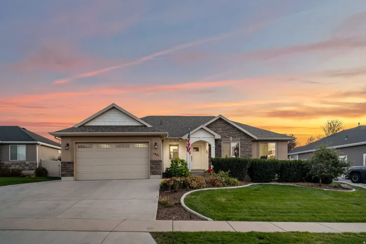 Exterior featuring stone and siding accents, an attached two-car garage, a concrete driveway, and a landscaped front yard with a manicured lawn