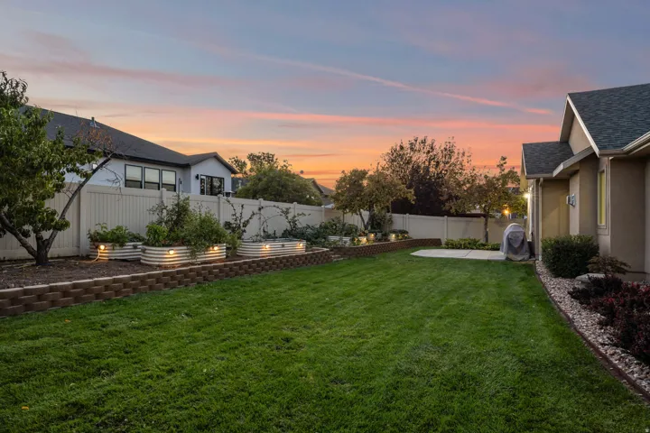 Expansive lawn with a concrete patio, bordered by decorative rock landscaping