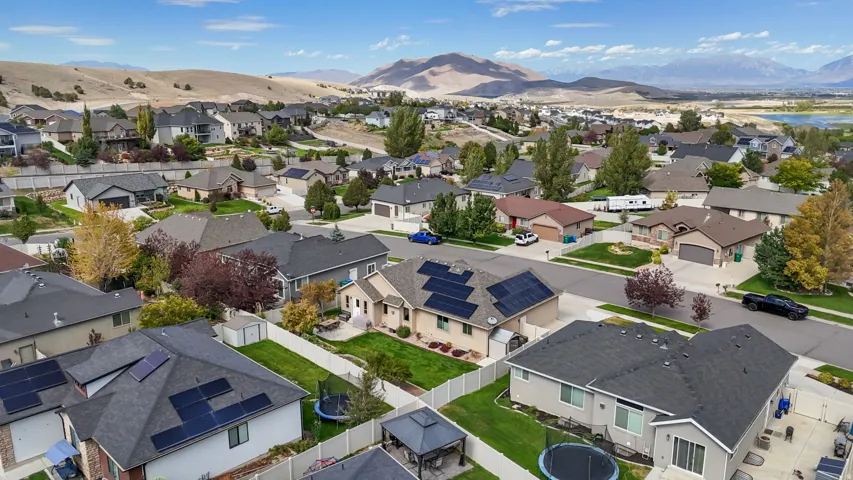 Residential neighborhood with mountain backdrop, established landscaping, and solar panels on multiple rooftops