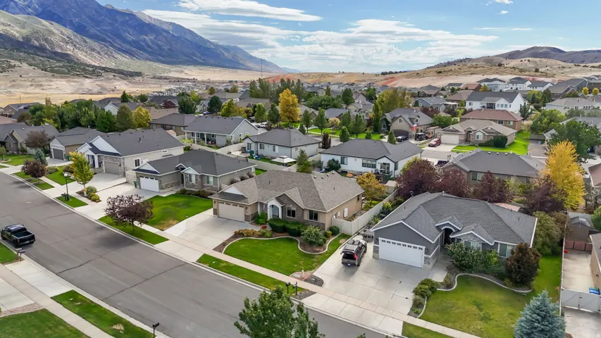 Residential neighborhood with paved streets and sidewalks, featuring single-story homes with attached garages, concrete driveways, and landscaped front yards