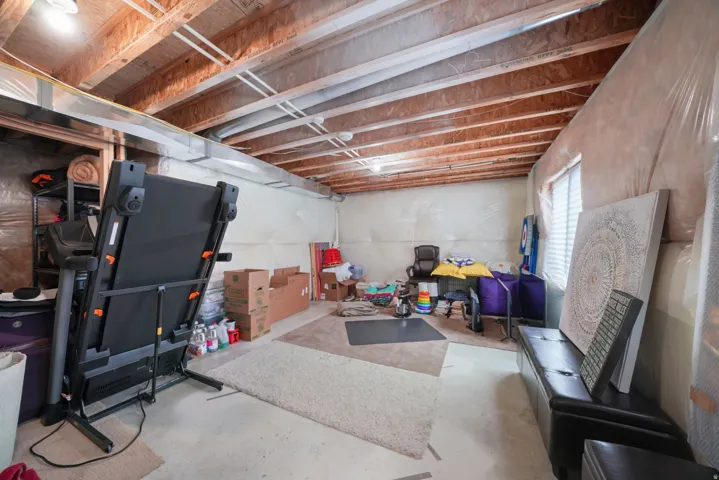 Unfinished basement space with exposed ceiling joists and a single window