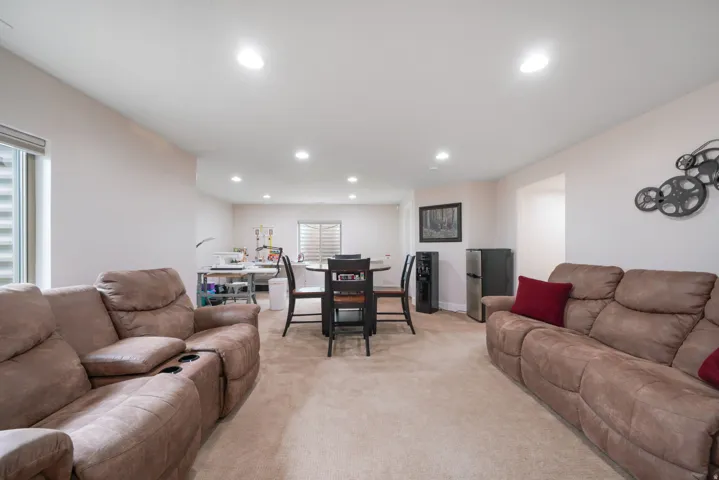 Recessed ceiling lighting illuminates a carpeted living space with multiple windows