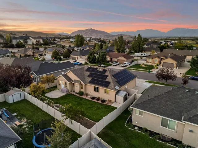 Single-story residence featuring a neutral-toned exterior, prominent solar panel array, and an asphalt shingle roof