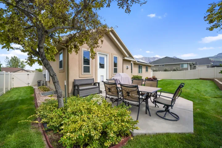 Expansive lawn area with mature landscaping, a concrete patio, and a privacy fence