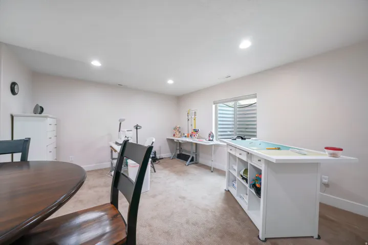 Recessed lighting, light-toned carpeting, and a window well for natural illumination