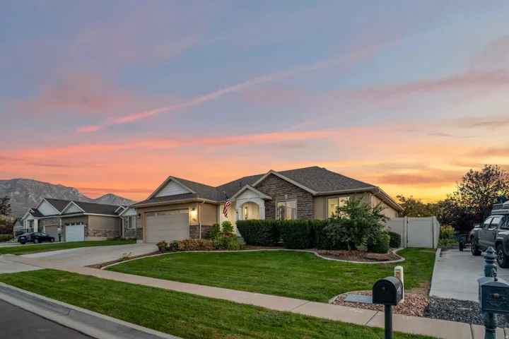 Single-story residence featuring a two-car garage, stone and stucco exterior, arched entry, and a manicured front lawn
