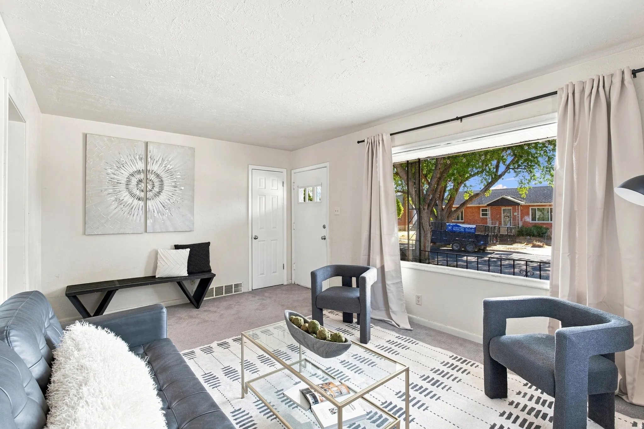 Light gray carpeting throughout, white painted walls, and a large front window with a black curtain rod