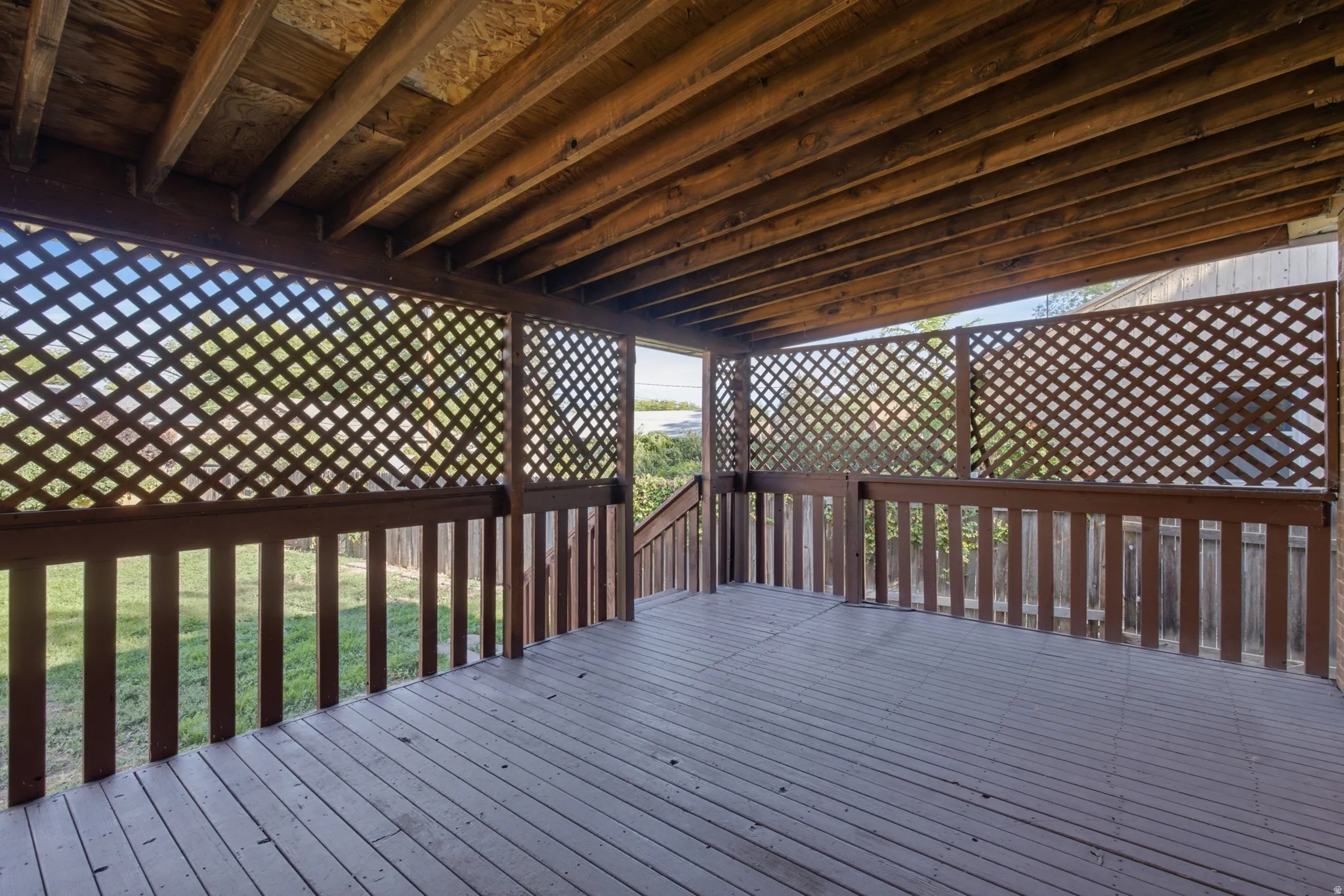 Covered wood deck with lattice privacy screens and wood railings
