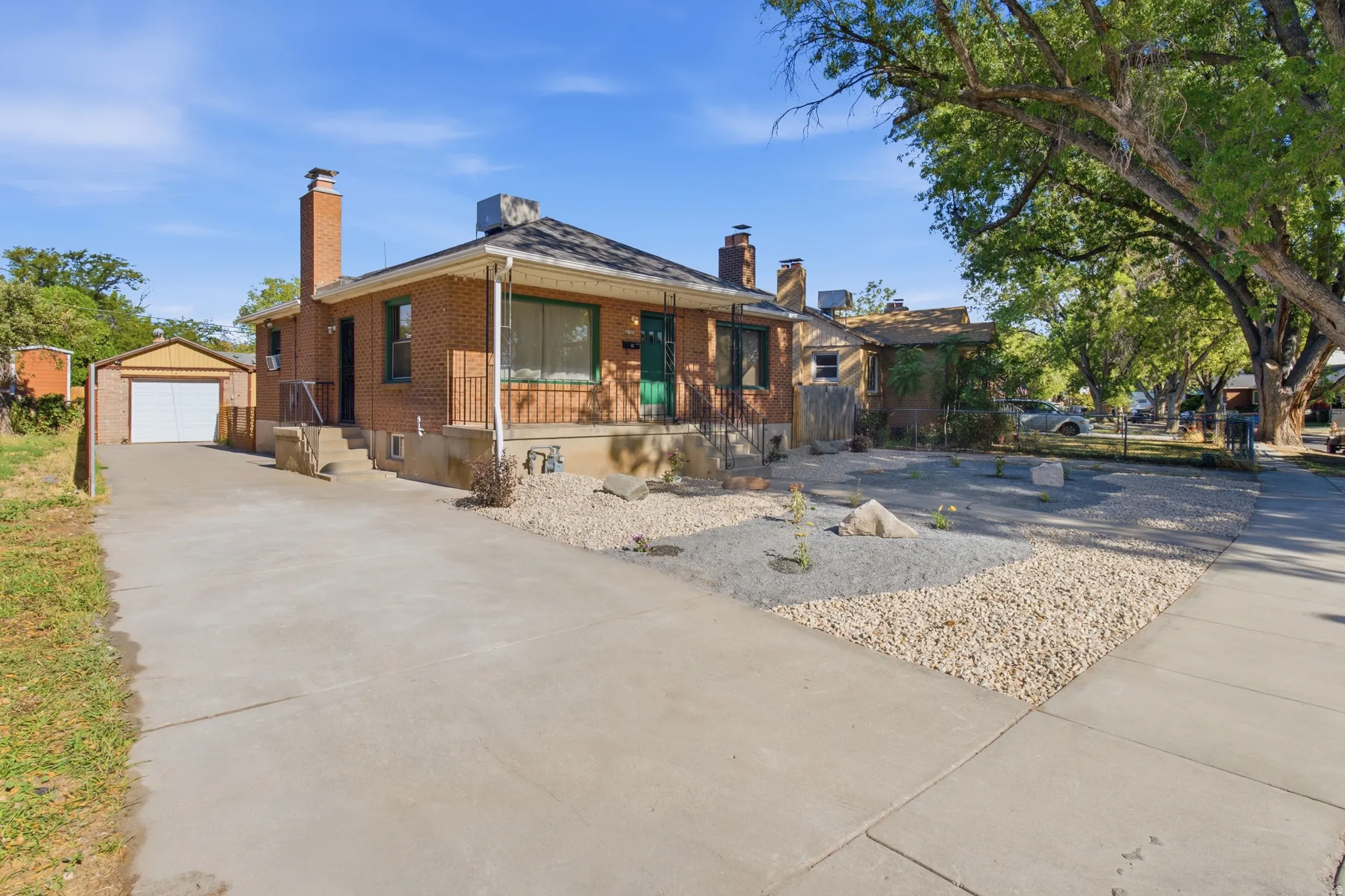 Brick exterior with a covered porch, an attached garage, a concrete driveway, and a xeriscaped front yard