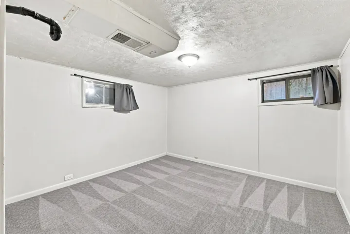 Light gray patterned carpeting, white painted walls, and a flush-mount ceiling light fixture