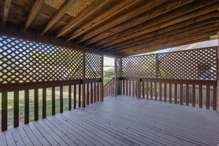 Covered wood deck with lattice privacy screens and wood railings