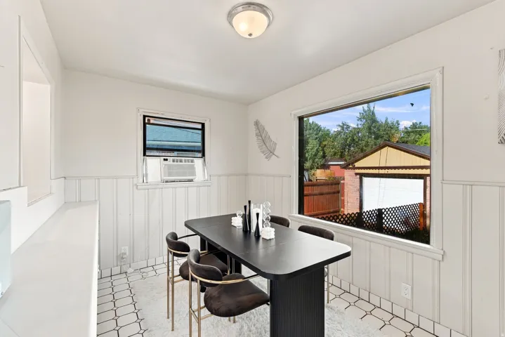 White paneled wall accents with a large picture window and white-tiled flooring